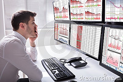 Sad Male Operator Looking At Graphs On Multiple Computer Screen Stock Photo