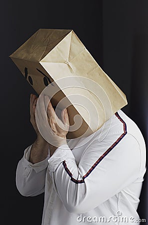 Sad man with a bag on his head, with a drawn crying emoticon. Stock Photo