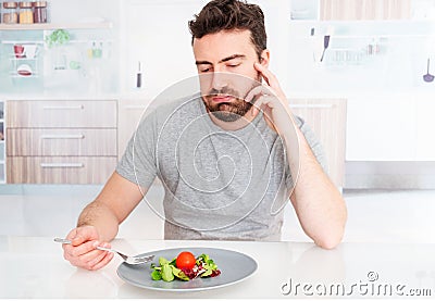 Sad man forced to eat salad for weight loss Stock Photo