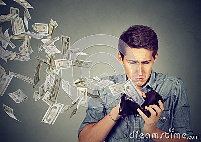 Sad man looking at wallet with money dollars flying away Stock Photo