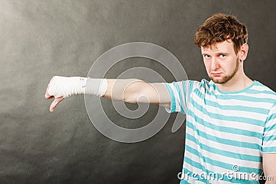 Sad man showing thumb down by bandaged hand. Stock Photo