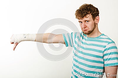 Sad man showing thumb down by bandaged hand. Stock Photo