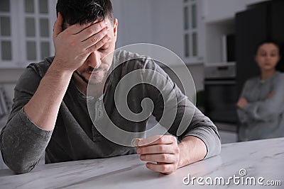 Sad man with wedding ring in kitchen. Couple on verge of divorce Stock Photo