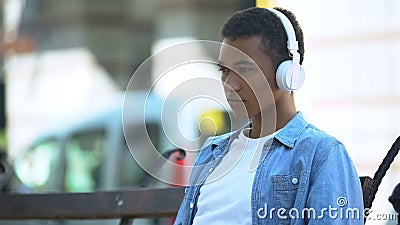 Sad mixed-race boy listening to favorite romantic song, yearning on bench Stock Photo