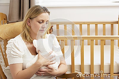 Sad Mother Sitting In Empty Nursery Stock Photo