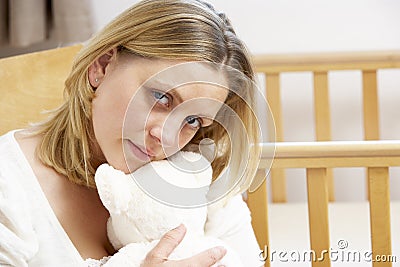 Sad Mother Sitting In Empty Nursery Stock Photo