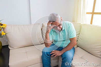 A sad old man with a headache who seems desperate and lonely at home Stock Photo