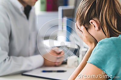 Sad patient visiting doctor. Young woman with stress or burnout getting help from medical professional or therapist. Stock Photo