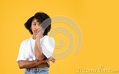 Sad pensive millennial black woman in casual looks at copy space, think, touch cheek Stock Photo