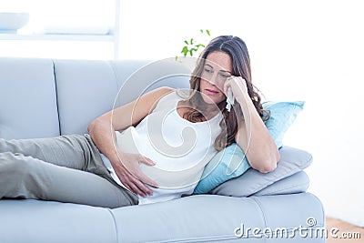Sad pregnant woman lying on sofa Stock Photo