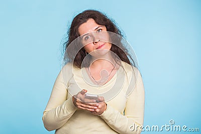 Sad and resentful woman waiting for excuses and explanations and is reproachfully looking on blue background. Stock Photo