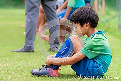 Soccer kid sitting on field side substitution bench doesn`t get to play in a competition match Stock Photo