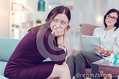 Sad sorrowful charming woman crying during a visit to phycologist. Stock Photo