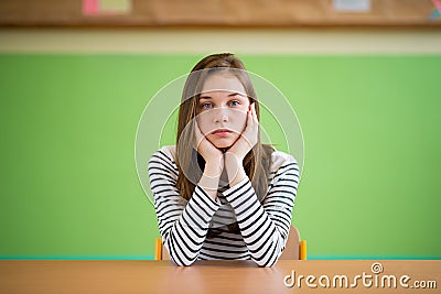 Sad student sitting in classroom with her head in hands. Education, high school, bullying, pressure, depression. Stock Photo