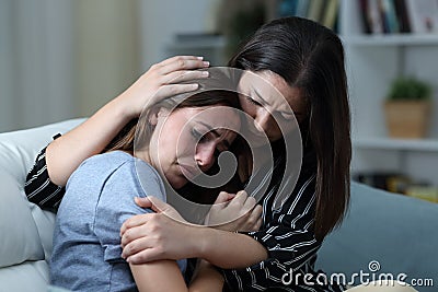 Sad teen crying being comforted by her sister at home Stock Photo