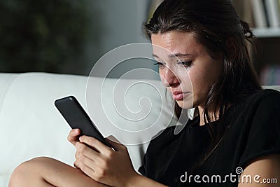 Sad teenager checking phone cyber bullying messages Stock Photo