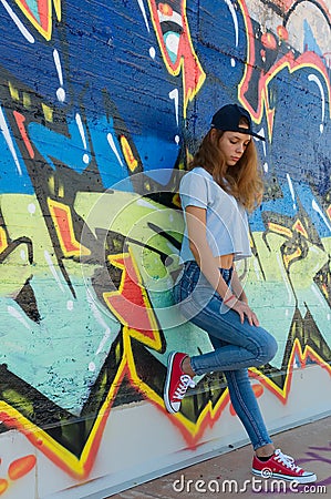 Sad teenager leaning against a graffiti wall Editorial Stock Photo