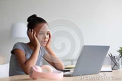 Sad tired bored pretty teenager african american girl pupil in headphones study at home with laptop Stock Photo