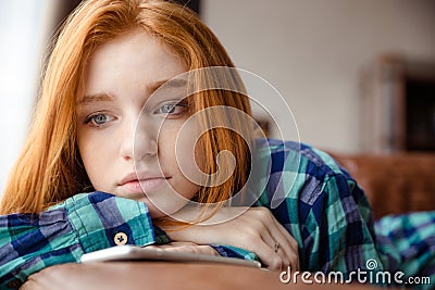 Sad tired young redhead lady thinking and listening to music Stock Photo