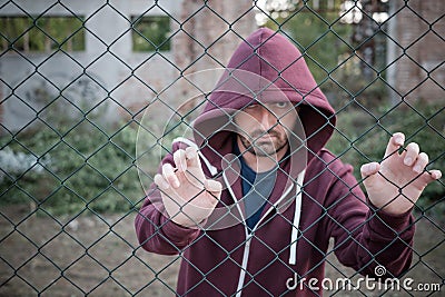 Sad and troubled boy against metal fence Stock Photo