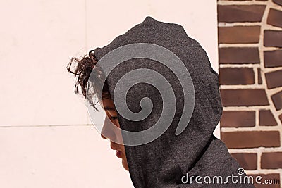 Sad troubled teenager school boy with hood on posing outdoor standing alone on the street Stock Photo