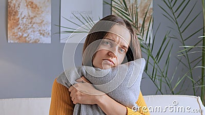 Sad unhappy worried bored woman sitting at home alone embracing pillow missing somebody being in bad mood looking at camera with Stock Photo