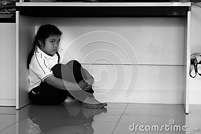 Sad upset unhappy boy kid hiding under the table. Stock Photo