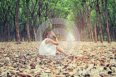 Sad woman hands off her face so sadly sitting on dry leaf in the Stock Photo