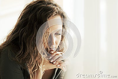 Sad woman with long curly hairs looking down Stock Photo