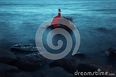 A sad woman near the sea in evening Stock Photo