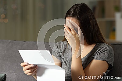 Sad woman reading a letter in the dark Stock Photo