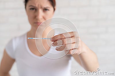 Sad woman shows a negative ovulation test. The concept of female infertility and low luteinizing hormone. Frustrated Stock Photo