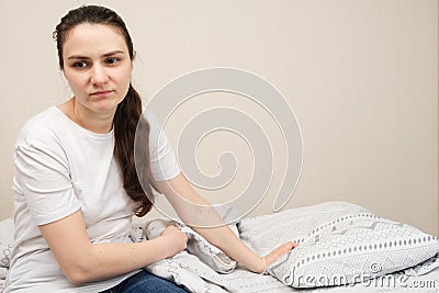 A sad woman sits on a bed, a place for text. Insomnia, impaired libido in women Stock Photo