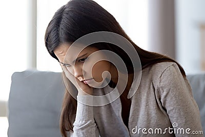 Sad woman thinking about problem sitting on couch at home Stock Photo