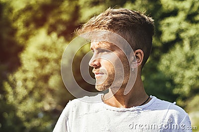 Sad, worried blond young man against trees Stock Photo