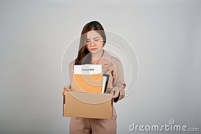 Sad young businesswoman holding a box full of her stuff, feeling sad after quitting her job Stock Photo