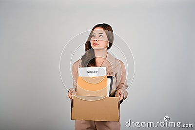 Sad young businesswoman holding a box full of her stuff, feeling sad after quitting her job Stock Photo