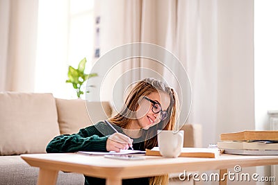 A sad young female student sitting at the table, studying. Stock Photo