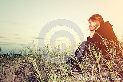 Sad young girl sitting alone on a grass outdoors,Sadness. Loneliness Stock Photo