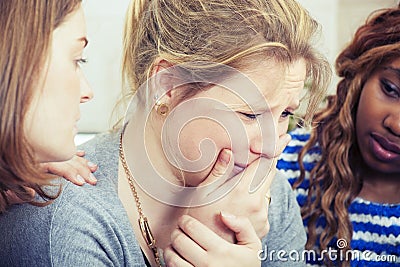 Sad young woman being comforted by friends Stock Photo