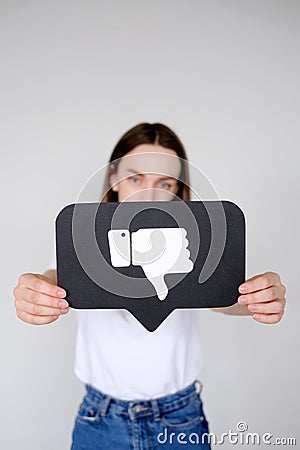 Sad young woman holding Dislike button icon of social media Stock Photo