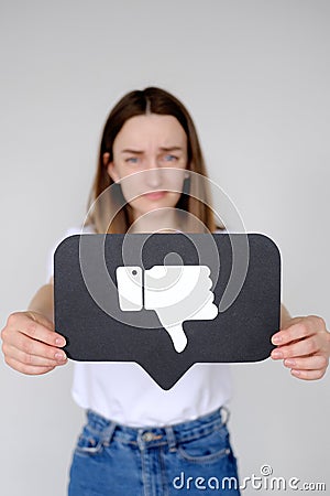 Sad young woman holding Dislike button icon of social media Stock Photo