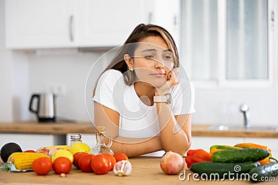Sad woman looking at vegetable at kitchen, dieting problems Stock Photo