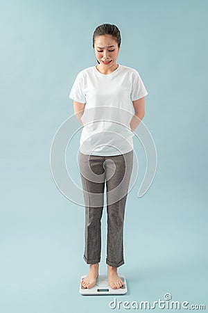 Sad young woman standing on scale. She is not satisfied with the result. Diet and healthy living concept Stock Photo
