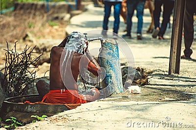 Sadhu is washed under running water near the road Editorial Stock Photo