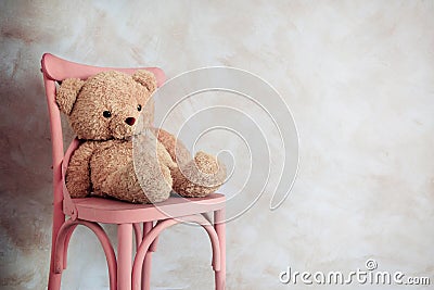 Sadness and Loneliness Concept. Lonely Teddy Bear Toy Siting Alone on Chair in House Stock Photo