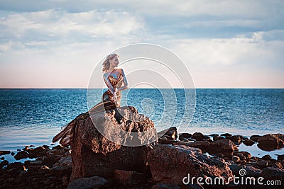 Sadness mermaid, nixie, water nymph sitting on stone Stock Photo