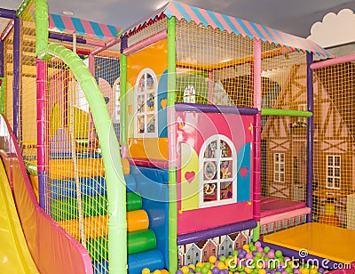 Safe colorful children's trampoline with a net and colorful balls in the form of a house on the playground, indoors Stock Photo