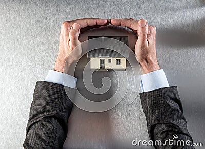 Safe insulation home with businessman hands protecting and securing roof Stock Photo