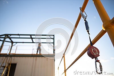 Safe work practices an inertia reel shock absorbing fall protection hook lanyard device clipping hanging on handrail Stock Photo